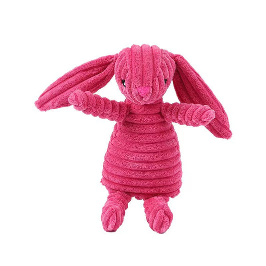 Pink corduroy plush bunny stuffed animal toy with long floppy ears sitting on a beige sofa, soft cuddly rabbit doll for kids and nursery decor.