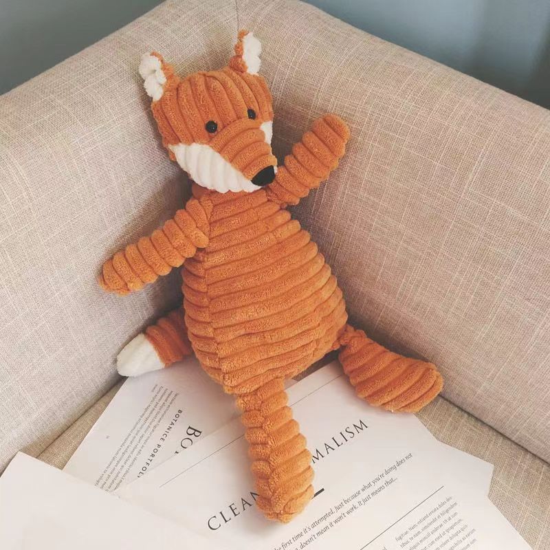 Plush fox toy on an open book with a neutral background