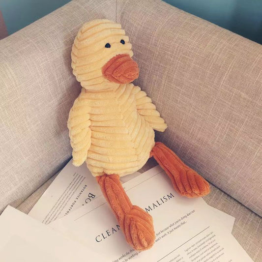 Plush duck toy on a book with a neutral background