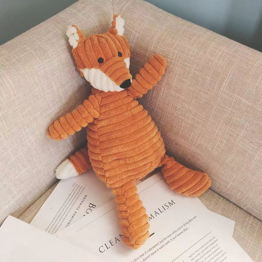 Plush fox toy on an open book with a neutral background